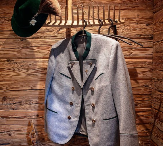 Garderobe Oberstdorfer Tradition Hut mit Gamsbart und graue Trachtenjacke an der Garderobe, die aus einem Holz-Rechen besteht.