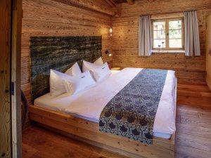 Im Schlafraum im Chalet Jägar wirkt Holz direkt beruhigend. Ein einladender Raum, alpine, stylische Einrichtung.