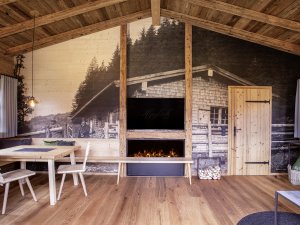 In dem Chalet Jägar sind Holz und ein großflächiges Wandbild von der Jagdhütte zu sehen. Ein einladender Raum mit stylischer Einrichtung.