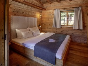 Im Schlafraum im Chalet Sennar wirkt Holz direkt beruhigend. Ein einladender Raum, alpine, stylische Einrichtung.