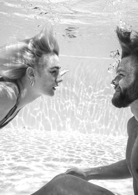 Zwei Menschen spielen unter Wasser und genießen eine gemeinsame, verspielte Zeit im Pool.