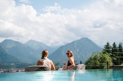 Frauen unterhalten sich auf Terrasse vor Pool