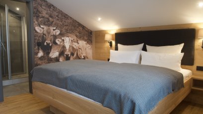 Modernes Zimmer mit komfortablem Bett und einzigartiger Wandgestaltung. Ideal für einen entspannenden Aufenthalt in der Natur.