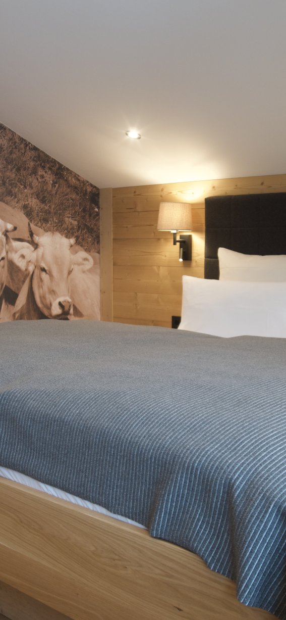 Elegantes Appartement mit Kuhmotiv im Landhausstil Modernes Zimmer mit komfortablem Bett und einzigartiger Wandgestaltung. Ideal für einen entspannenden Aufenthalt in der Natur.