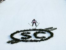 Skispringer fliegt über das Logo des Skiclub Oberstdorf