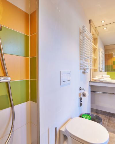 Mit neuem Farbkonzept, wandhohem Spiegel & großer Dusche überzeugt das Bad im Explorer Hotel Garmisch