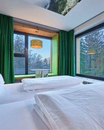 Im nachhaltigen Explorer Hotel Garmisch dominiert die Farbe grün, aus dem Bett hast Du einen tollen Blick in die Natur. Gemütliche Betten und toller Ausblick aus den Design-Zimmern im Explorer Hotel Garmisch in Farchant in Oberbayern.