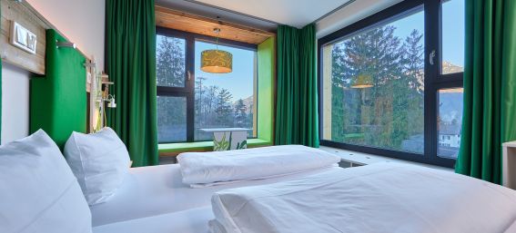 Gemütliche Betten und toller Ausblick aus den Design-Zimmern im Explorer Hotel Garmisch in Farchant in Oberbayern.