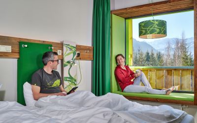 Ob Du gemütlich im Bett liegst oder die Füße auf der Sitzbank im Panoramafenster hochgelegt hast, aus dem Zimmer im Explorer Hotel Garmisch hast Du immer einen tollen Ausblick in die Natur und die Berge.
