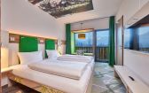 Modernes Zimmer im Explorer Hotel Garmisch mit toller Aussicht , bequemem Bett und frischen Farben.