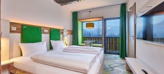 Modernes Zimmer im Explorer Hotel Garmisch mit toller Aussicht , bequemem Bett und frischen Farben.