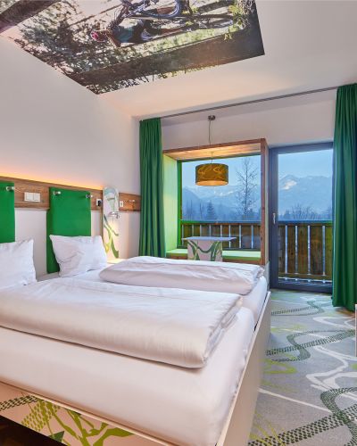 Modernes Zimmer im Explorer Hotel Garmisch mit toller Aussicht , bequemem Bett und frischen Farben.