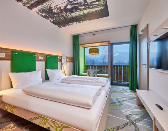 Modernes Zimmer im Explorer Hotel Garmisch mit toller Aussicht , bequemem Bett und frischen Farben.