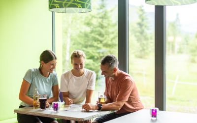 Sommerurlaub im Explorer Hotel Garmisch: Plane entspannt vor großem Panoramafenster Deine Wanderung in der Explorer Lounge.