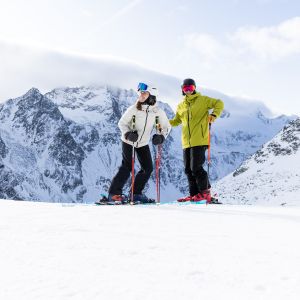 Ein sportliches Paar beim Skifahren im Skigebiet Sölden im Ötztal genießt die Aussicht auf die Berge Skifahren in Sölden ist ein Muss für alle ambitionierten Skifahrer. Das beste Basislager dafür ist das Explorer Hotel Ötztal in Umhausen.