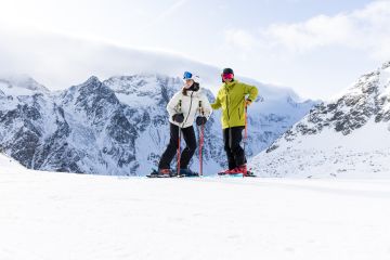 Una coppia di sportivi si gode il panorama montano mentre scia nella stazione sciistica di Sölden, nella valle dell'Ötztal. Sciare a Sölden è un'esperienza imperdibile per tutti gli sciatori più ambiziosi. Il punto di partenza ideale è l'Explorer Hotel Ötztal a Umhausen.