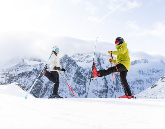 Sportliches Skifahrer Paar macht lustige Skigymnastik mit Ski und Stöcken im Skigebiet Sölden im Ötztal Im Skigebiet Giggijoch kann man auch super Skigymnastik und Späße einbauen.