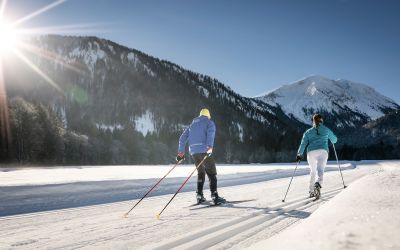Zwei Langläufer sind auf den Loipen rund um Bayrischzell mit ihren Skiern unterwegs.