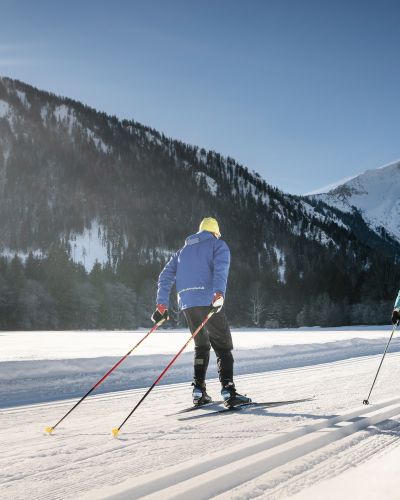 Zwei Langläufer sind auf den Loipen rund um Bayrischzell mit ihren Skiern unterwegs.