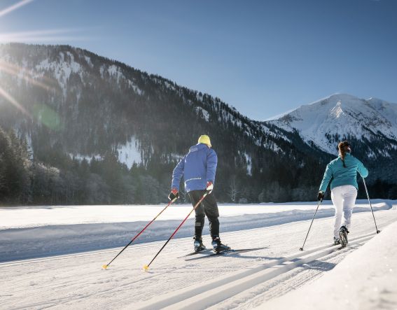 Zwei Langläufer sind auf den Loipen rund um Bayrischzell mit ihren Skiern unterwegs.