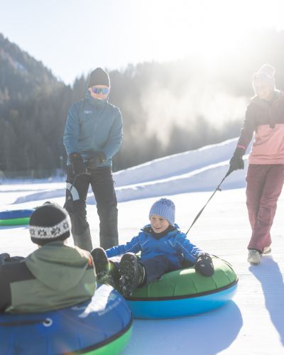 Familie mit Snowtubes im Ötztal – Winterspaß auf der Schneebahn Familie zieht Snowtubes auf einer sonnigen Winterbahn im Ötztal – gemeinsames Schneeabenteuer mit Kindern in Tirol