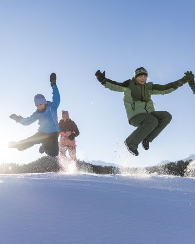 Familie springt im Schnee im Ötztal – Winteraction mit Kindern Familie springt gemeinsam über eine Schneekuppe im Ötztal – energiegeladene Winteraction mit Kindern in Tirol