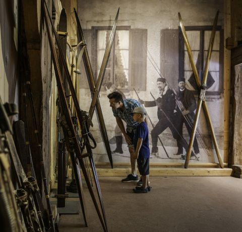 Familie schaut sich alte Skier in einem Museum an. Es ist das Markus Wasmeier Freilichtmuseum am Schliersee.