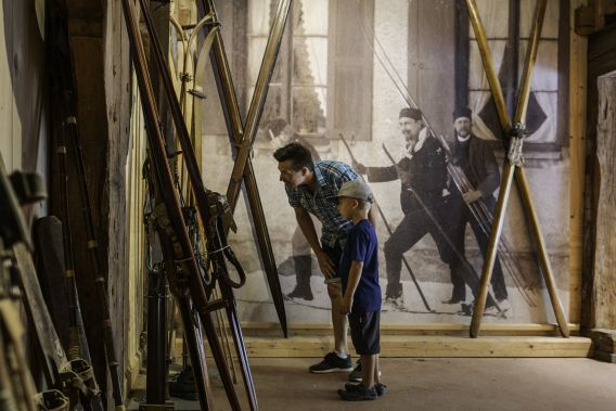Familie schaut sich alte Skier im Markus Wasmeier Freilichtmuseum an. Familie schaut sich alte Skier in einem Museum an. Es ist das Markus Wasmeier Freilichtmuseum am Schliersee.