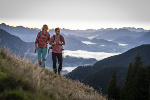 Pärchen Wandert in der Abenddämmerung und hat einen fantastischen Blick in die Bayerischen Alpen.