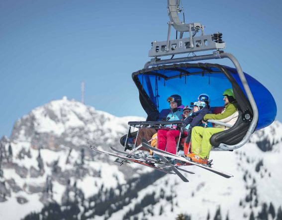Skifahrer fahren mit einer Gondel den Berg hinauf.