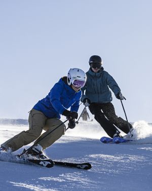Twee mensen skiën in de stralende zon de Sudelfeldberg af.