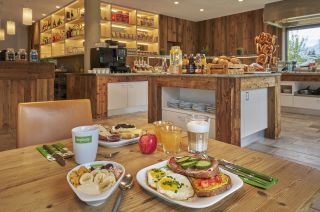 Gedeckter Frühstückstisch mit Müsli, Obst und Kaffee im Explorer Hotel. Gedeckter Frühstückstisch vor dem Buffet mit Müsli, frischem Obst, Kaffee und Säften.