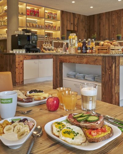 A breakfast table set in front of the buffet with muesli, fresh fruit, coffee and juices.