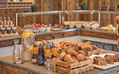 Auswahl an frischen Brötchen, Brot, Säften und weiteren Speisen am Frühstücksbuffet.