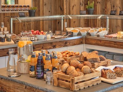 Auswahl an frischen Brötchen, Brot, Säften und weiteren Speisen am Frühstücksbuffet.