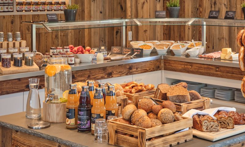 Auswahl an frischen Brötchen, Brot, Säften und weiteren Speisen am Frühstücksbuffet.