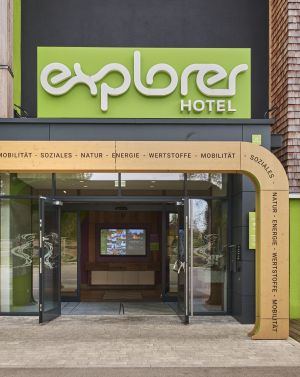 Frontaler Blick auf den markanten, grün gestalteten Eingang eines Hotels der Explorer Hotels.