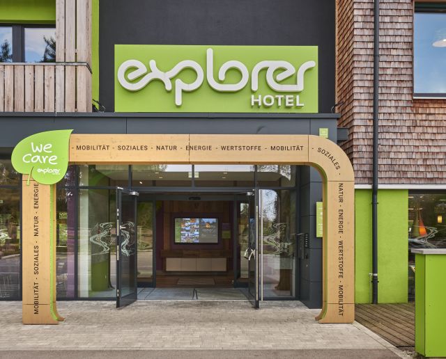 Frontaler Blick auf den markanten, grün gestalteten Eingang eines Hotels der Explorer Hotels.
