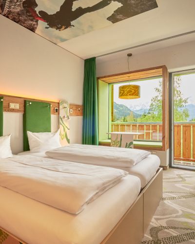 Modernes Doppelzimmer mit Holzelementen, grünen Farbakzenten und direktem Zugang zum Balkon.