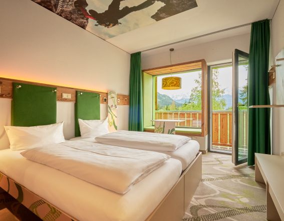 Modernes Doppelzimmer mit Holzelementen, grünen Farbakzenten und direktem Zugang zum Balkon.