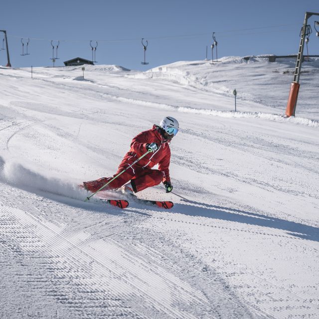 Skifahrer allein auf der Skipiste im Skigebiet Rossfeld neben einem Skilift im Winterurlaub.