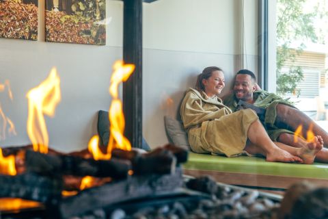 Několik lidí relaxuje v salonku s krbem v Monte Mare Schliersee.
