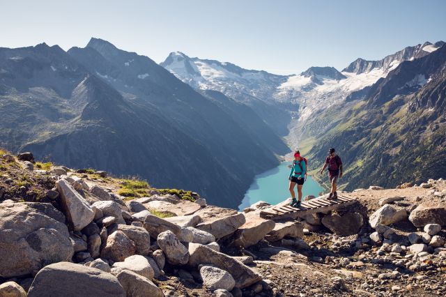 Wanderung im Bereich der Olperer Brücke im Zillertal mit Holzsteg, felsiger Landschaft und Blick auf den Schlegeisspeicher
