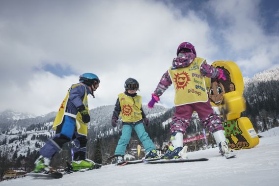 Drei Kinder beim Skifahren am Tannerfeld in Bayrischzell Drei Kinder üben das Skifahren am Tannerfeld in Bayrischzell vor winterlicher Bergkulisse