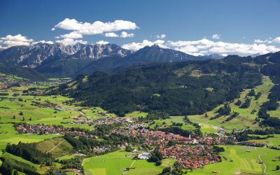 Hoch oben siehst Du Nesselwang mal von einer anderen Seite. Umgeben von grünen Wiesen, Wäldern und Bergen liegt das Explorer Hotel Neuschwanstein in Nesselwang.