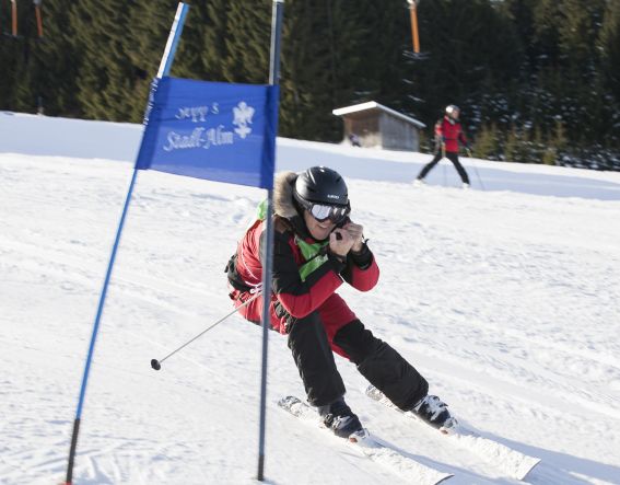 Young skiers give it their all in a ski race during a winter holiday in Nesselwang, Allgäu, Germany. The perfect accommodation, with breakfast and a sports spa and sauna, is the Explorer Hotel Neuschwanstein.