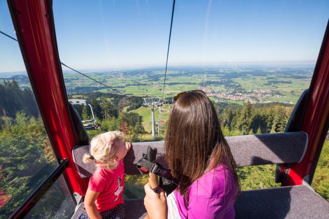 Blick auf die grünen Wiesen des Allgäus von der Gondel aus Sommerurlaub mit der Familie im Explorer Hotel Neuschwanstein. Wandern und Natur erleben im Familienurlaub in Bayern. Mit der Alpspitzbahn in Nesselwang kommt Ihr bequem auf die Alpspitze.
