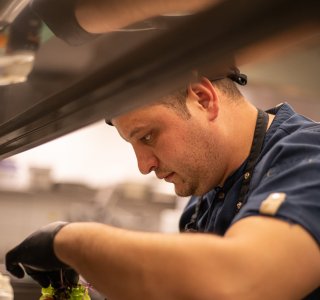 Ein Koch bereitet ein Gericht in der Restaurantküche vor.