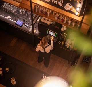 Blick von oben auf die Barkeeperin, die gerade einen Kaffee an der Kaffeemascine zubereitet.