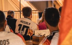 Die Menschen schauen ein Fußballspiel in der Fasshalle an und tragen Trikots. Stimmung ist lebhaft und konzentriert.